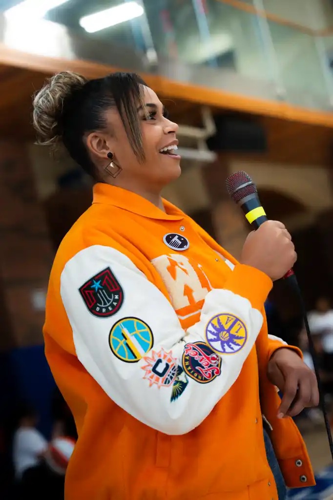 A Point Goddess speaker addressing a room of young athletes with a microphone