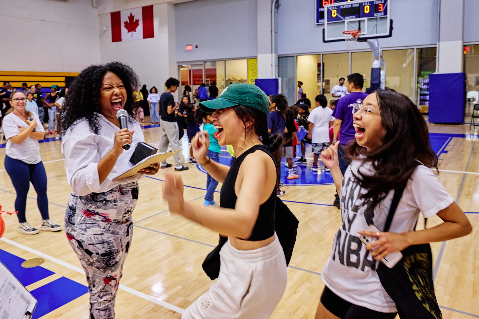 Host with a microphone cheering with two laughing participants at a Point Goddess event