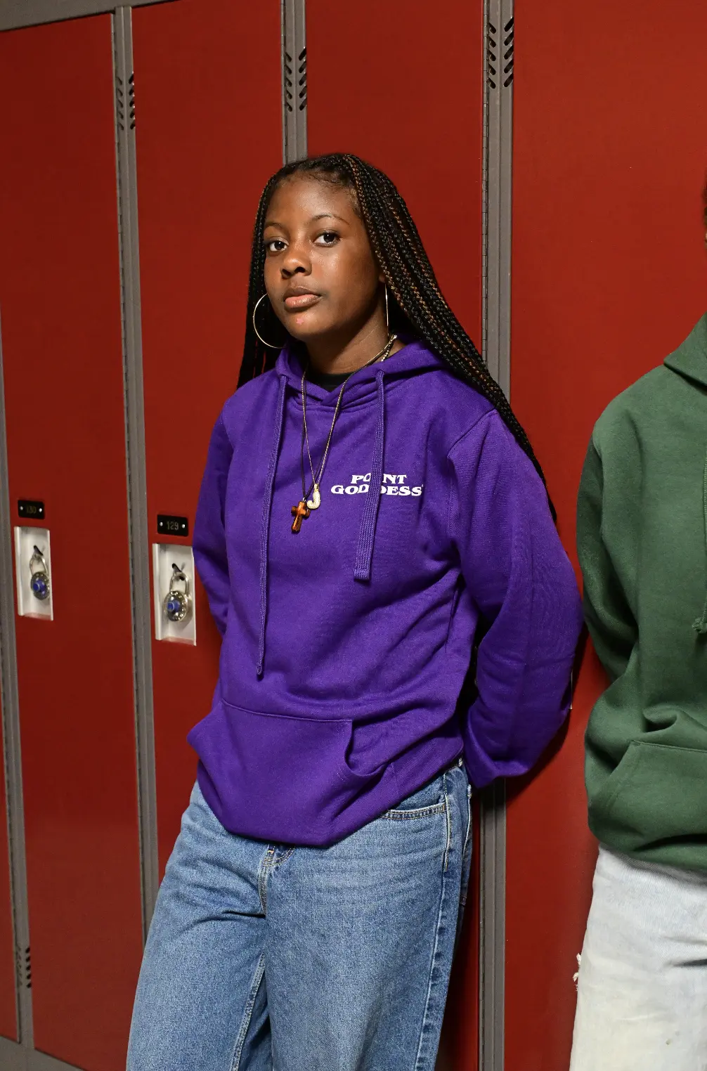 Athlete wearing a purple Point Goddess hoodie in front of school lockers