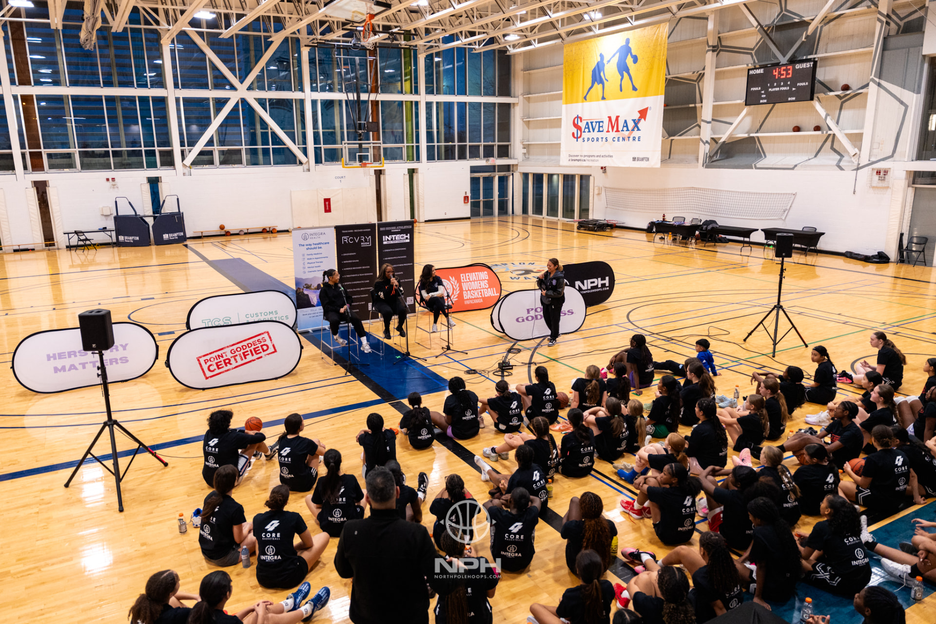 A packed gym of young athletes seated on the floor during a Point Goddess camp